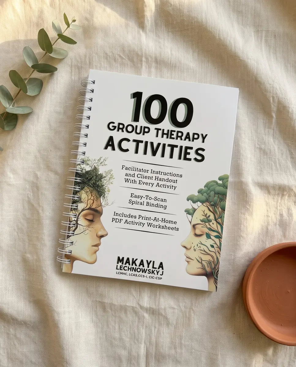 Spiral-bound 100 Group Therapy Activities book by Makayla Lechnowskyj on bone linen with a eucalyptus sprig and terracotta dish